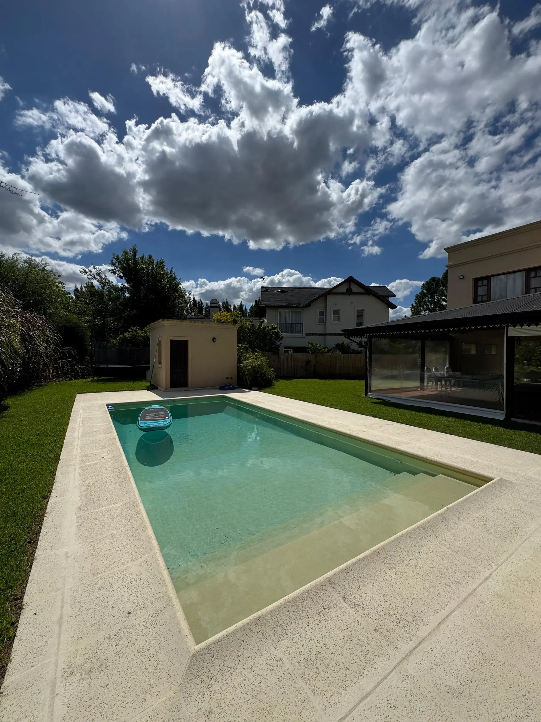 Piscina rectangular con escalinata a todo lo ancho y solárium color arena