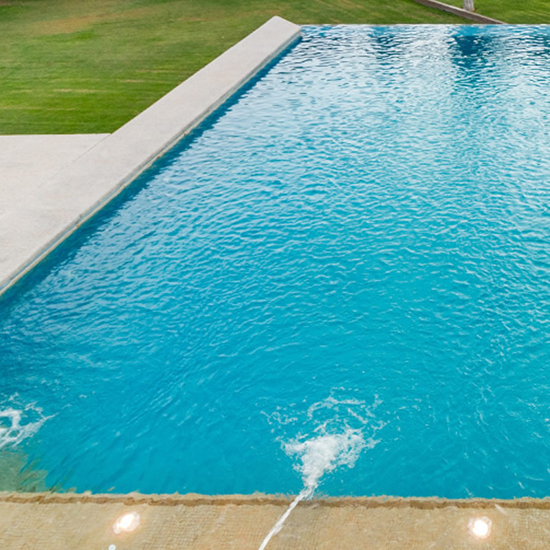 Piscina rectangular con revestimiento celeste y césped
