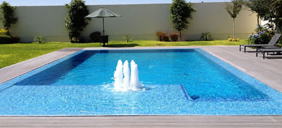 Piscina rectangular con borbotones, solárium y jardín