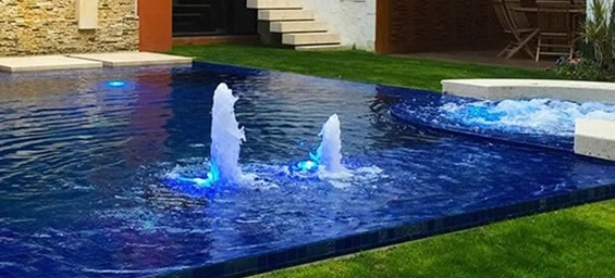 Piscina con borbotones iluminados y muro de piedra