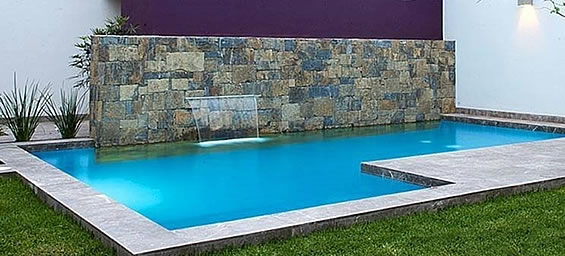 Piscina en L con borde atérmico rodeada de césped